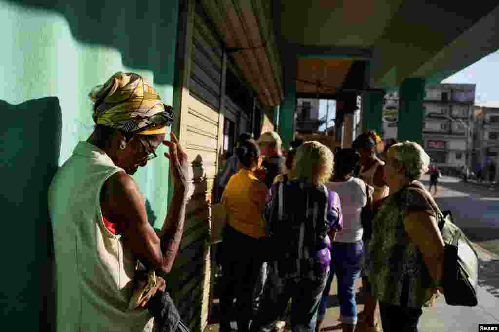 Una mujer protege su rostro del sol mientras espera con otros clientes fuera de un banco, en La Habana, Cuba, 4 de septiembre de 2024. REUTERS/Norlys Pérez