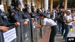 Manifestante protesta frente a formación de Policía Nacional Bolivariana en Caracas. (AFP)