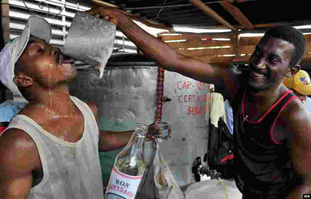 Dos hombres beben y bromean mientras venden cerveza en Santiago de Cuba. ,