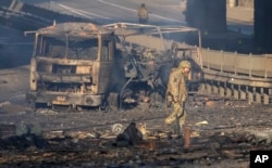Un soldado ucraniano se desplaza entre los restos de un camión militar incendiado en una calle en Kiev, Ucrania