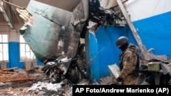 Un soldado ucraniano pasa junto a una pieza de la cola de un bombardero Su-34 ruso sobre un edificio dañado en Járkiv, Ucrania, el 8 de marzo de 2022.