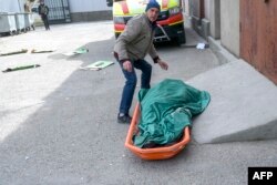 Voluntario traslada cadáver de una anciana víctima de bombardeo ruso en la región de Mykolaiv, Ucrania
