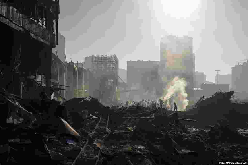 Bomberos extinguen un fuego cerca de un centro comercial bombardeado en Kyiv, Ucrania. Foto: AP/Felipe Dana.