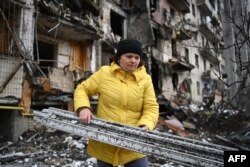 Mujer ucraniana recoge escombros provocados por los ataques rusos en un barrio de Kiev