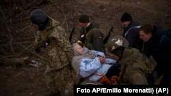 Soldados y milicianos ucranianos cargan a una mujer bajo ataques de artillería rusa en Irpin en las afueras de Kyiv, Ucrania, el 7 de marzo de 2022.