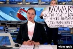 Marina Ovsyannikova (detrás, con el cartel), empleada de la emisora estatal Canal Uno, (Captura de video/CNN)