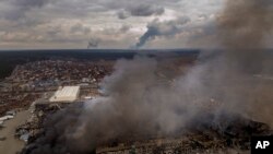 Una fábrica y una tienda arden en llamas después de ser bombardeadas el domingo, en Irpin, a las afueras de Kiev, Ucrania. (AP/Emilio Morenatti)