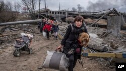 Ucranianos cruzan por una ruta improvisada bajo un puente destruido en la localidad de Irpin, el domingo 6 de marzo de 2022. (AP/Oleksandr Ratushniak)
