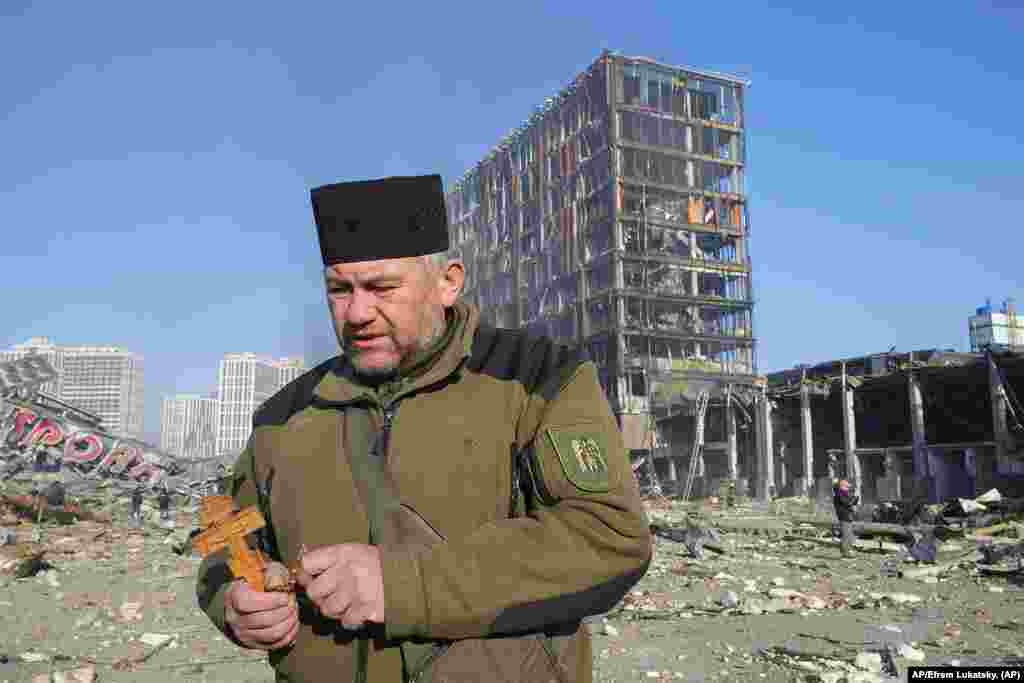 Un sacerdote reza en las ruinas de un centro comercial destrozado después de un bombardeo ruso en Kyiv, Ucrania. Foto: AP/Efrem Lukatsky.