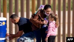 Una madre migrante cubana le da agua a su hija tras cruzar la frontera por el muro que separa a Estados Unidos y México, en Yuma, Arizona. RINGO CHIU / AFP/Archivo)