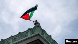 Un estudiante ondea una bandera palestina en la azotea del Hamilton Hall de la Universidad de Columbia, en Nueva York, Estados Unidos, este martes 30 de abril. (REUTERS/David Dee Delgado)
