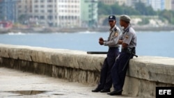 Dos policías descansan en el muro del malecón habanero.