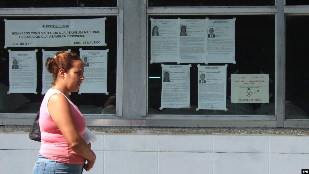 Una mujer camina junto a carteles alusivos a las elecciones de los delegados a las asambleas nacionales y provinciales del Poder Popular en Cuba. 
