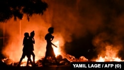 Personas pasan junto a un fuego encendido por manifestantes durante una protesta contra la falta de energía y los apagones en el barrio de Lawton, en La Habana, el 14 de mayo de 2026. 