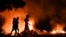Personas pasan junto a un fuego encendido por manifestantes durante una protesta contra la falta de energía y los apagones en el barrio de Lawton, en La Habana, el 14 de mayo de 2026. 
