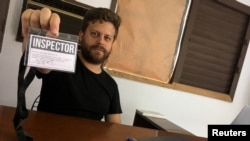 El artista cubano Leandro Feal sostiene una tarjeta de presentación que dice: "inspector", un performance que denuncia la figura de control artístico amparada bajo el Decreto Ley 349. 