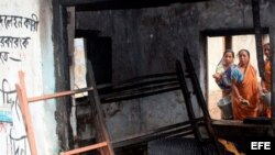 Mujeres observan una de las casas que han sido quemadas por un grupo de maoístas