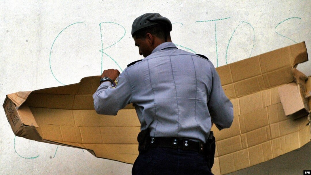 Fotografía de archivo de un policía cubano tapando mensajes antigubernamentales