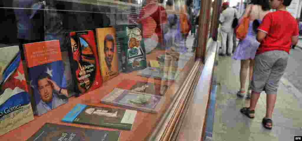 Varias personas pasan frente a una librería donde se expone un libro sobre el presidente de Venezuela, Hugo Chávez en La Habana.