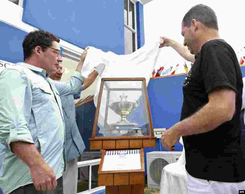 John (d) y Patrick Hemingway (i), nietos de Ernest Hemingway, participan junto al comodoro del Club Náutico Internacional Marina Hemingway, Jose Migues Scrich (c), en la develación de la copa trofeo del torneo de pesca.