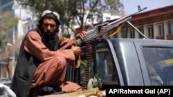 Un combatiente del Talibán apostado con una ametralladora frente al principal ingreso al palacio presidencial en Kabul (Afganistán)