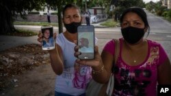 FOTO ARCHIVO. Servilia Pedroso, a la derecha, madre del estudiante Eloy Bárbaro Cardoso, de 18 años, y Yaquelin Cruz, madre de Dariel Cruz, muestran las fotografías de sus hijos detenidos durante las protestas del 11 de julio de 2021. (Foto AP/Ramón Espinosa)