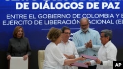 La representante del gobierno colombiano Vera Grabe, izquierda, y el comandanteELN), Pablo Beltrán, intercambian su acuerdo de extensión del alto el fuego firmado en La Habana, Cuba, el martes 6 de febrero de 2024. (Foto AP/Ramón Espinosa)