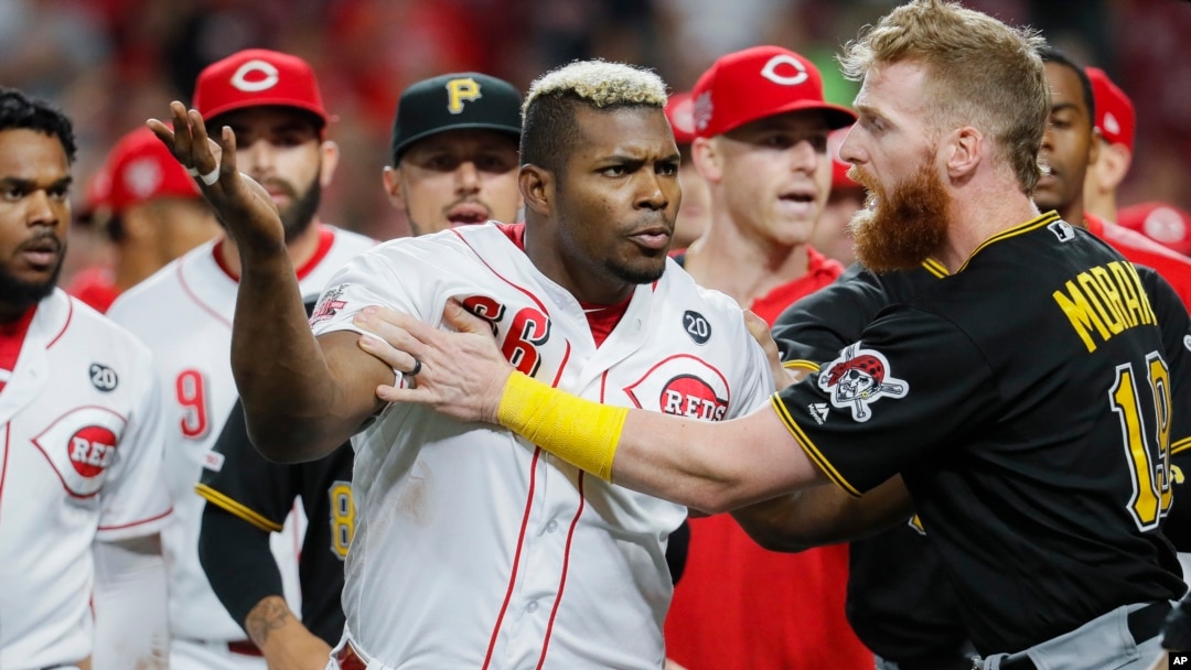 Yasiel Puig (66) de los Rojos de Cincinnati es contenido por Colin Moran de los Piratas de Pittsburgh, el martes 30 de julio de 2019. (AP Foto/John Minchillo)