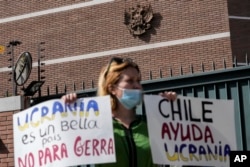 Una ucraniana residente en Chile sostiene carteles contra la invasión rusa de Ucrania, frente a la embajada rusa en Santiago, Chile, el jueves 24 de febrero de 2022. (Foto AP/Esteban Félix