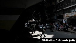 Una mujer con tapaboca cruza una calle en Caracas, el 26 de diciembre de 2021. [Foto: AP/Archivo]