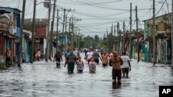 Residentes de Batabanó caminan por las calles inundadas por las lluvias de la tormenta Helene.