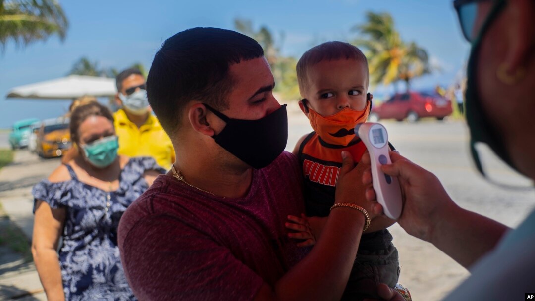 Un policía toma la temperatura a viajeros en un punto de control de coronavirus en La Habana. (AP Photo/Ramon Espinosa)