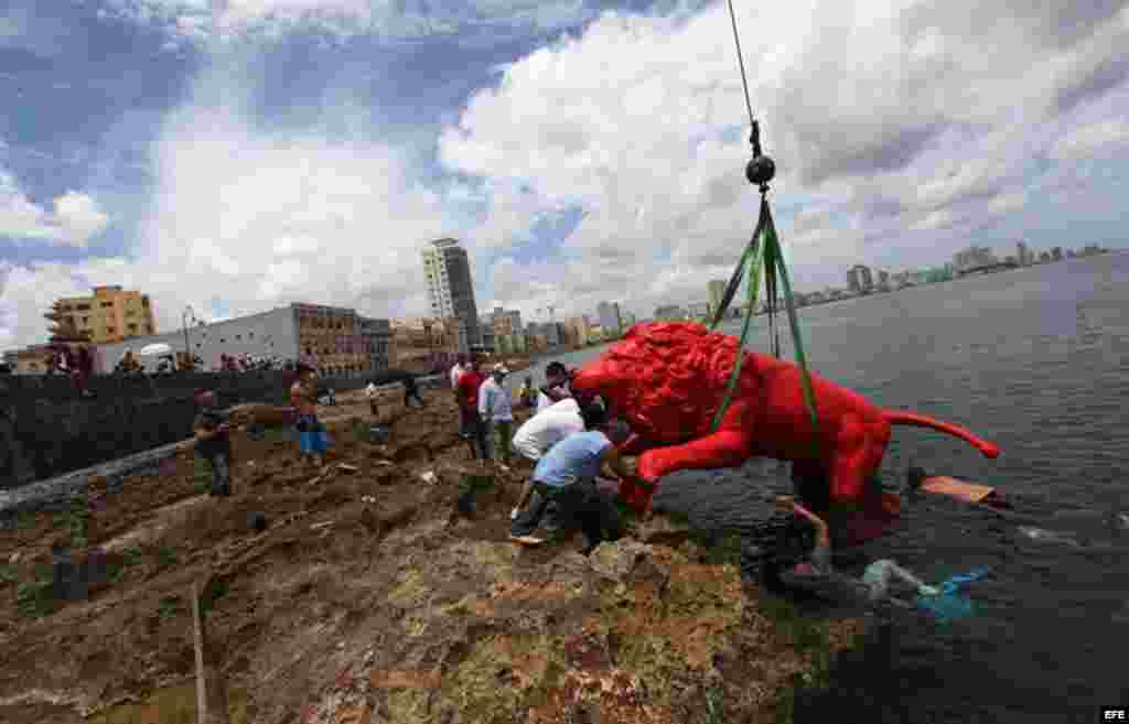 El artista pl&aacute;stico cubano Roberto Fabelo (i) posa junto a un le&oacute;n rojo creado por &eacute;l que conforma la obra "Garras en la piedra" que se instala en los arrecifes del malec&oacute;n de La Habana (Cuba). Esta pieza forma parte 