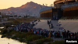 Migrantes hacen fila cerca del muro fronterizo tras cruzar el río Bravo para entregarse a agentes de la Patrulla Fronteriza de EE. UU. y solicitar asilo en la ciudad estadounidense de El Paso, Texasel 14 de diciembre de 2022. REUTERS/Jose Luis Gonzalez
