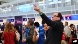 Empleados de servicio al cliente de la aerolínea Delta dan información a viajeros de vuelos retrasados mientras hacen fila en el aeropuerto Internacional Minneapolis/St. Paul.