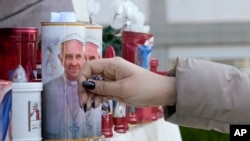 Una mujer deja un rosario junto a velas adornadas con la imagen del papa Francisco, en el exterior del hospital Agostino Gemelli de Roma. (AP/Gregorio Borgia)