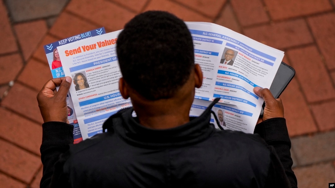 Un hombre lee material electoral antes de votar durante el último día de votación anticipada, el sábado 2 de noviembre de 2024, en Charlotte, Carolina del Norte (Foto AP/Mike Stewart)