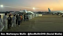 Una fila de inmigrantes a punto de abordar el vuelo de deportación. 