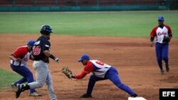 Ramón Lunar Armenteros (2-d) saca out al estadounidense DJ Stewart durante la serie amistosa jugada entre el equipo Cuba y una selección universitaria estadounidense en julio de 2014. 