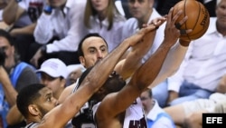 El jugador de los Spurs Tim Duncan (izda) lucha por el balón con Dwyane Wade (dcha) de los Heat durante el cuarto partido de las Finales de la NBA.