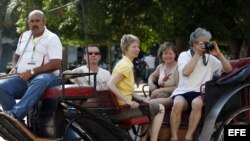 Un grupo de turistas pasea en un coche tirado por caballos, por una calle de La Habana, Cuba. Archivo.