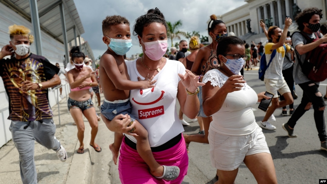 Una mujer con un niño en brazos marcha frente al Capitolio de La Habana durante una manifestación contra Miguel Díaz-Canel en La Habana, el 11 de julio de 2021. (Adalberto Roque/AFP).