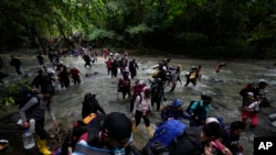 Migrantes, en su mayoría venezolanos, cruzan un río durante su viaje a través del Tapón del Darién desde Colombia a Panamá, con la esperanza de llegar a EEUU, el 15 de octubre de 2022. (Foto AP/Fernando Vergara, Archivo).