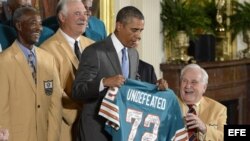 El presidente estadounidense, Barack Obama (c), recibe una camiseta de los Delfines de Miami que dice "Invicto", acompañado del exentrenador Don Shula (d), los exjugadores Paul Warfield (i) y Larry Csonka (2-i).