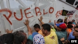 Manifestantes de la oposición venezolana gritan consignas a integrantes de la Guardia Nacional Bolivariana de Venezuela durante una marcha contra la sentencia del TSJ.