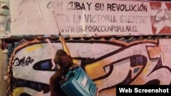 Activistas cubanos borran con pintura carteles en Santiago de Chile que celebran el centenario del natalicio de Fidel Castro. (Captura de video de @AngelRCuba/X) 