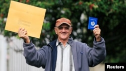 Un cubano muestra su pasaporte luego de recibir la visa de EEUU. (Archivo/REUTERS/Jaime Saldarriaga)