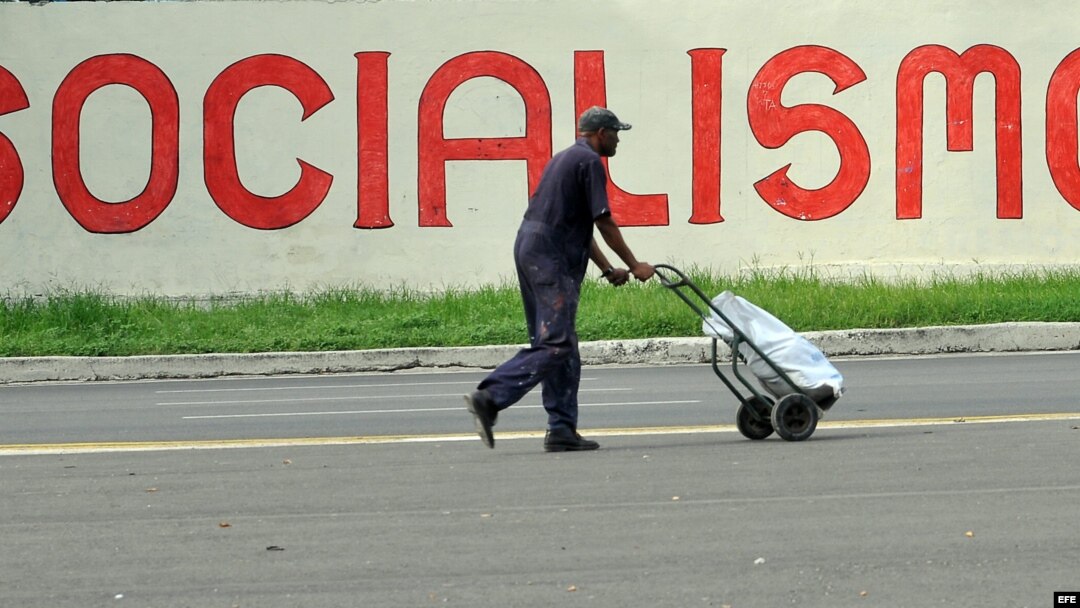 Un hombre camina frente a un cartel alusivo al socialismo en La Habana.