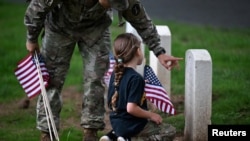 Un soldado y su hija colocan banderas en el Cementerio Nacional de Arlington, en Virginia, EEUU, en conmemoración del Día de los Caídos.