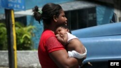 Una cubana carga a su hijo pequeño.